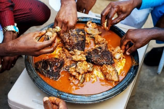 Hands reaching into a shared pot of soup